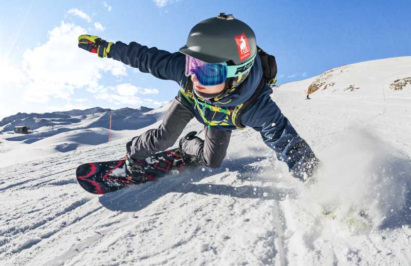 Woman snowboarding with a Nordeau sticker on her helmet.