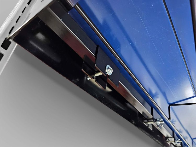 Close-up of a metal assembly featuring a blue panel mounted to a black steel frame using bolts and brackets. The image highlights fastening techniques and structural integration.