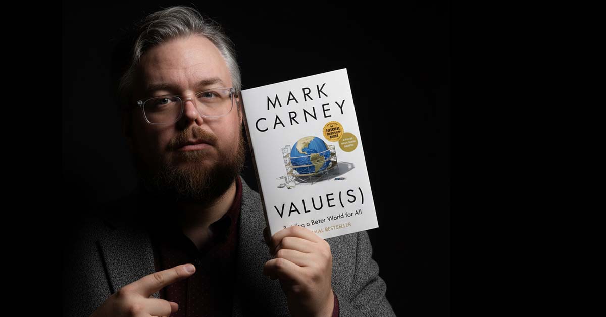 AI edited. A portrait of Colin Finkle in dramatic lighting holding and pointing at the book Values by Mark Carney.