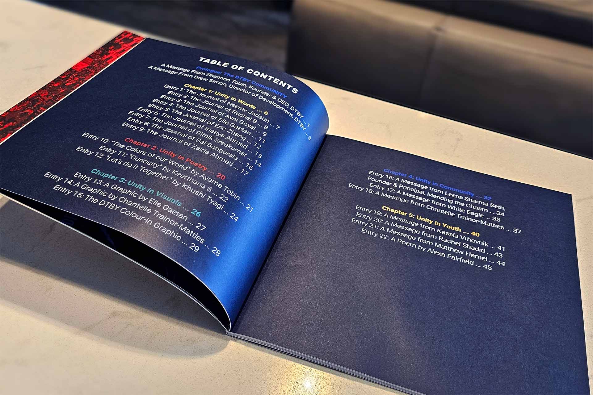 Open booklet showing table of contents with color-coded chapters on unity in words, poetry, visuals, community, and youth.