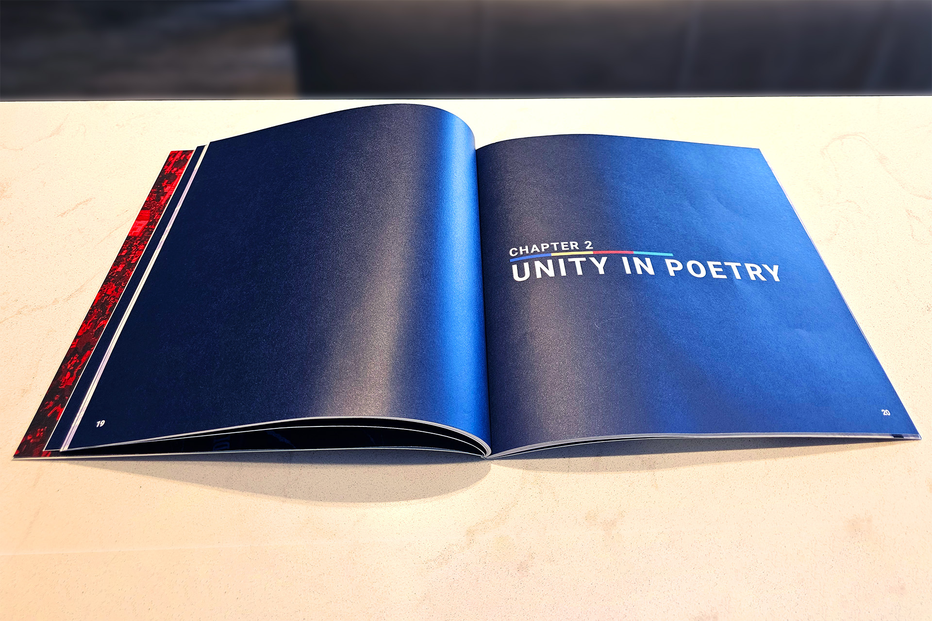 Open book showing chapter title “Unity in Poetry” on a dark blue background with red-to-blue decorative line.