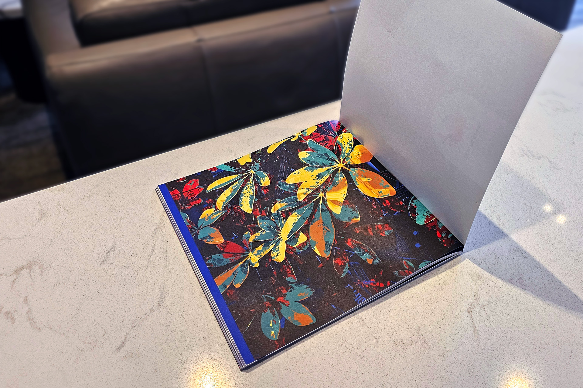 Open book showing abstract artwork of colorful leaves in red, yellow, green, and blue on a dark background.