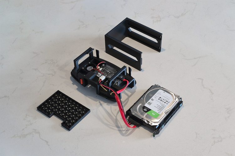 A hand sliding an 8 TB Seagate BarraCuda drive in its HP caddy sideways out of the open chassis, with red SATA and power cables trailing to the board below.