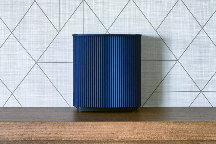 Front view of the navy-blue ridged enclosure on a wooden shelf, with a black base and small rubber feet showing beneath the shroud.